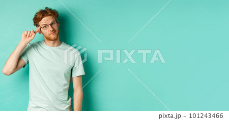 Skeptical redhead man scolding someone stupid or crazy, pointing finger at head and staring at camera, standing over mint background Skeptical redhead man scolding someone stupid or crazy, pointing finger at head and staring at camera, standing over mint background 101243466