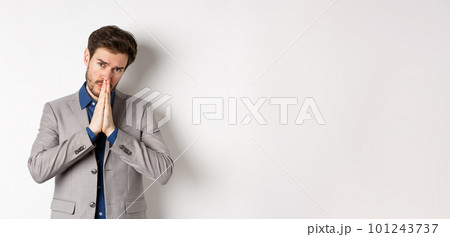 Please help. Pleading man in suit asking for favour, begging you, standing on white background 101243737