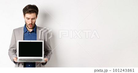 Handsome caucasian businessman in suit showing empty laptop screen, demonstrate promo, standing on white background 101243861