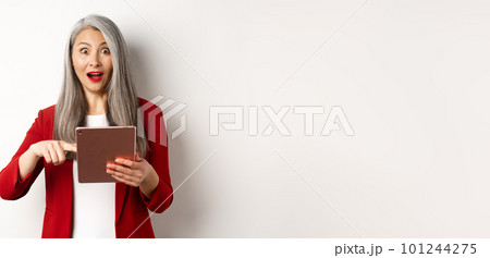 Business. Surprised female senior employer pointing at digital tablet screen, staring amazed at camera, checking out online promotion, white background 101244275