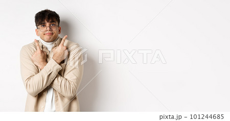 Confused funny guy in glasses pointing fingers aside, showing two variants and look indecisive, cant choose, standing on white background 101244685