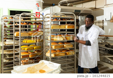 Baker pushing trolley with baked bread 101244815