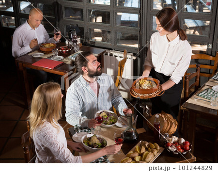 Beautiful couple eating out at a restaurant while young and obliging waitress is serving them dishes 101244829