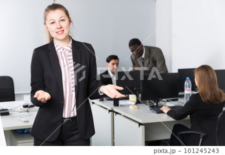 Positive businesswoman standing in office near colleagues 101245243