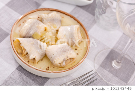 on checkered tablecloth plate with appetizer - rolls of salted Atlantic herring fillet with onions 101245449