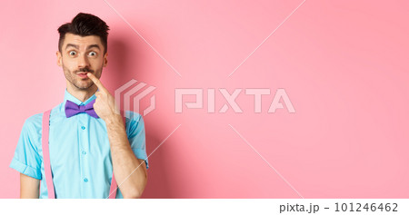 Intrigued happy guy touching lip, looking at camera pensive, making choice what to buy, standing over pink background Intrigued happy guy touching lip, looking at camera pensive, making choice what to buy, standing over pink background 101246462