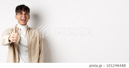 Nice one. Happy young man laughing and showing thumb up, like something good, standing on white background, complimenting you Nice one. Happy young man laughing and showing thumb up, like something good, standing on white background, complimenting you 101246488