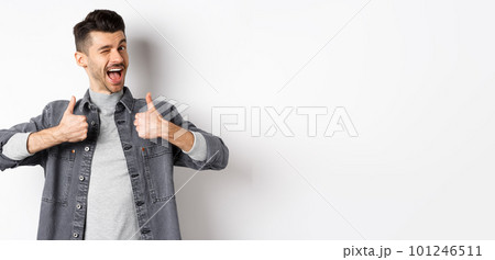 Happy young man with moustache winking and showing thumbs-up, recommending something, praise good thing, making compliment, standing on white background 101246511
