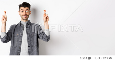 Hope dream come true. Positive and handsome guy making wish with fingers crossed, looking hopeful and smiling at camera, waiting results, standing on white background Hope dream come true. Positive and handsome guy making wish with fingers crossed, looking hopeful and smiling at camera, waiting results, standing on white background 101246550