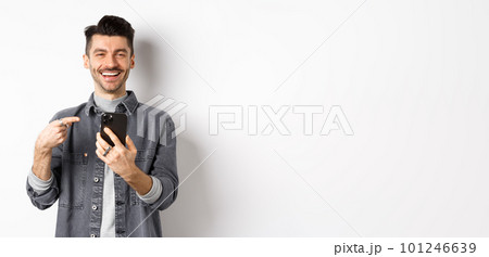 Happy handsome caucasian man with moustache pointing finger at smartphone, smiling and showing good deal online on mobile phone, standing pleased against white background Happy handsome caucasian man with moustache pointing finger at smartphone, smiling and showing good deal online on mobile phone, standing pleased against white background 101246639