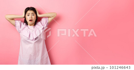 Frustrated asian teen girl panicking, holding hands on head and screaming scared, standing anxious on pink background Frustrated asian teen girl panicking, holding hands on head and screaming scared, standing anxious on pink background 101246643