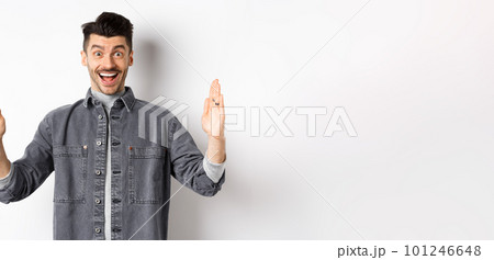 Happy guy with moustache showing big size with proud excited smile, shaping large object, standing in jacket on white background 101246648