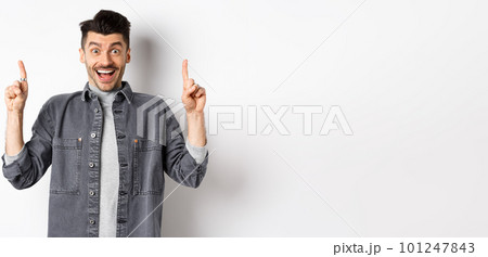Excited handsome guy pointing fingers up, smiling happy and showing special deal, standing on white background Excited handsome guy pointing fingers up, smiling happy and showing special deal, standing on white background 101247843