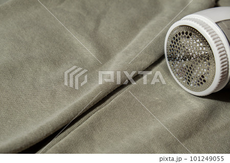 Anti-pilling razor. Device for shaving pellets clothes. Anti-Plush fabric Shaver. Electric portable sweater pill defuzzer Lint remover from acrylic or wool sweater. Sustainability lifestyle fashion Anti-pilling razor. Device for shaving pellets clothes. Anti-Plush fabric Shaver. Electric portable sweater pill defuzzer Lint remover from acrylic or wool sweater. Sustainability lifestyle fashion 101249055