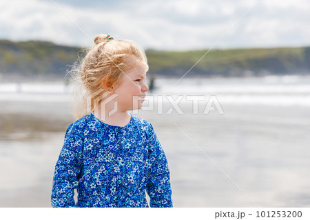 Little cute toddler girl at the Ballybunion surfer beach, having fun on with playing on west coast of Ireland. Happy child enjoying Irish summer and sunny day with family. 101253200