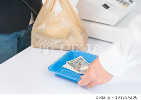 客にお釣りの紙幣と小銭・レシートをトレイに乗せて渡す店員の手元 客にお釣りの紙幣と小銭・レシートをトレイに乗せて渡す店員の手元 101254206