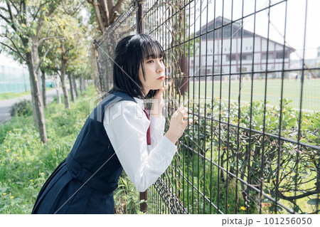 フェンスの前で応援する女子高生 101256050
