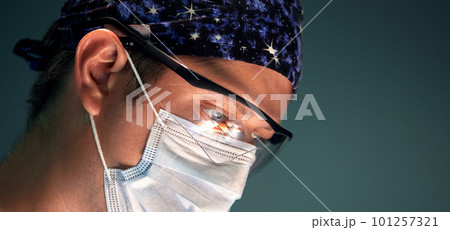 Portrait of a surgeon in the operating room against the background of a lamp, the doctor performs an operation, the fight against cancer and malignant tumors, modern medicine, copy space 101257321