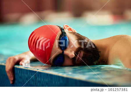 The swimmer rests with his head on the edge of the pool, the swimmer during a break in training makes a rest with his head on the side of the pool The swimmer rests with his head on the edge of the pool, the swimmer during a break in training makes a rest with his head on the side of the pool 101257381