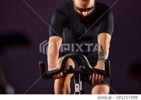 Portrait of a man on an exercise bike in the gym, a man with a beard and glasses on an exercise bike. Fitness man using exercise bike during cardio workout in crossfit gym. Portrait of a man on an exercise bike in the gym, a man with a beard and glasses on an exercise bike. Fitness man using exercise bike during cardio workout in crossfit gym. 101257399