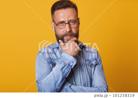 Man with a beard and a radiant skin tone stands in a studio