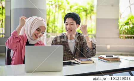 Happy Asian Muslim woman and Asian male college students celebrating exam score together. 101259038