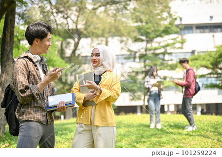 Happy Asian male college student talking with his Muslim female friend in the campus park. 101259224