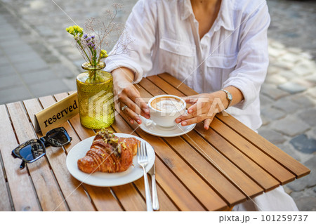 A woman has reserved a table for breakfast on the cafe's summer terrace. a crispy croissant with coffee 101259737