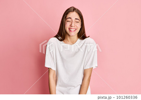 Happiness. Portrait of young positive, beautiful girl in white t-shirt posing, smiling against pink studio background. Celebration Happiness. Portrait of young positive, beautiful girl in white t-shirt posing, smiling against pink studio background. Celebration 101260336