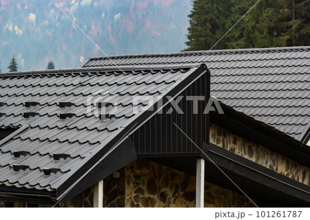 House with new brown metal tile roof and rain gutter. Metallic Guttering System, Guttering and Drainage Pipe Exterior House with new brown metal tile roof and rain gutter. Metallic Guttering System, Guttering and Drainage Pipe Exterior 101261787