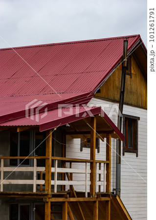 House with new brown metal tile roof and rain gutter. Metallic Guttering System, Guttering and Drainage Pipe Exterior House with new brown metal tile roof and rain gutter. Metallic Guttering System, Guttering and Drainage Pipe Exterior 101261791