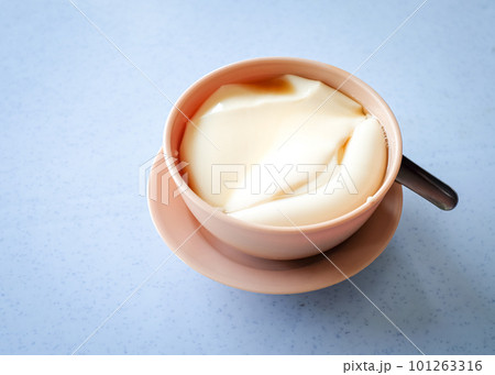 Tau foo fah (Soy bean pudding) in a bowl on top of a table. 101263316
