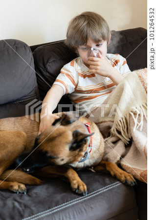 Sick child on the sofa at home with pet 101264532
