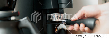 Close-up of male hand holding portfilter near coffee grinder Close-up of male hand holding portfilter near coffee grinder 101265080