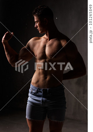 Athlete bodybuilder trains in the studio in the rain. 101265849