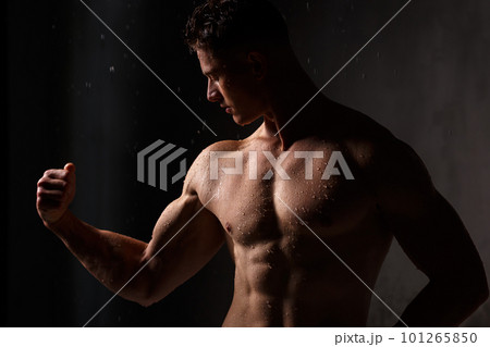 Athlete bodybuilder trains in the studio in the rain. 101265850
