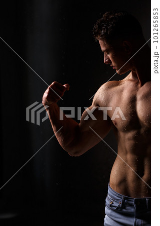Athlete bodybuilder trains in the studio in the rain. 101265853