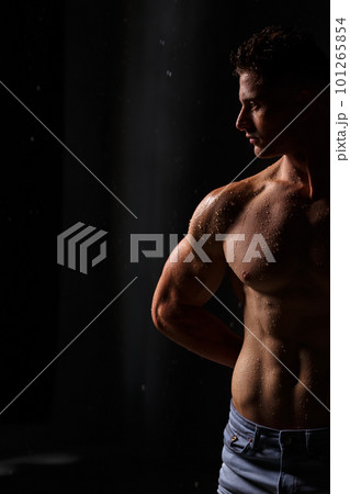 Athlete bodybuilder trains in the studio in the rain. 101265854