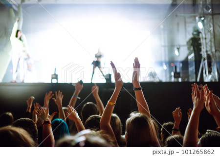 Crowd with raised hands at music festival. Fans enjoying rock concert with light show clapping hands 101265862