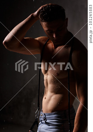 Athlete bodybuilder trains in the studio in the rain. 101265883