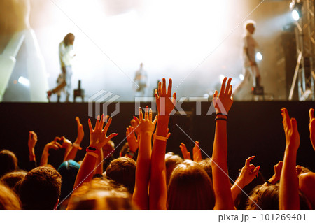 Crowd with raised hands at music festival. Fans enjoying rock concert with light show, clapping. 101269401