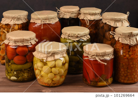 Jars with variety of mushrooms. Canned marinated mushrooms in glass jars. Preserved mushrooms on wooden table.  101269664