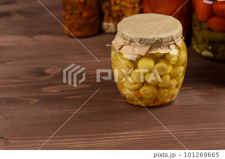 Marinated canned mushrooms champignon in front of variety of mixed conserved vegetables. Organic conserved food. Copy space. Marinated canned mushrooms champignon in front of variety of mixed conserved vegetables. Organic conserved food. Copy space. 101269665