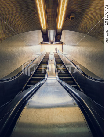 Lone man climbing out on a subway escalator. Symmetrical underground moving staircase Lone man climbing out on a subway escalator. Symmetrical underground moving staircase 101270473