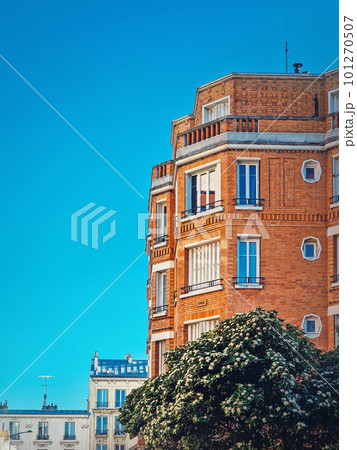 Beautiful orange brick building with a blooming tree at the bottom under a clear blue sky background in Asnieres-sur-seine a suburb of Paris, France Beautiful orange brick building with a blooming tree at the bottom under a clear blue sky background in Asnieres-sur-seine a suburb of Paris, France 101270507