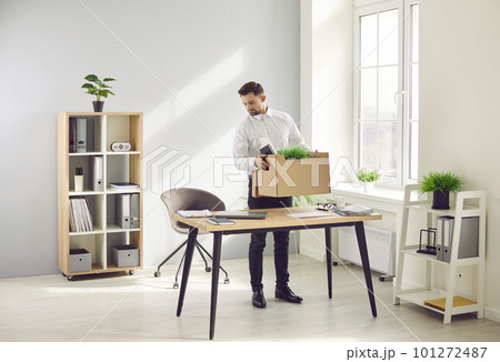 Portrait of employee with moving box of his belongings in his hands standing near his workplace. 101272487