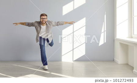 Happy young man in casual clothes standing on one leg while doing fitness exercises 101272493