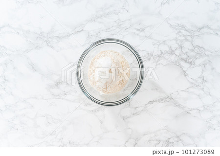 Flat lay. Mixing ingredients in a large glass mixing bowl to bake banana oatmeal muffins. 101273089