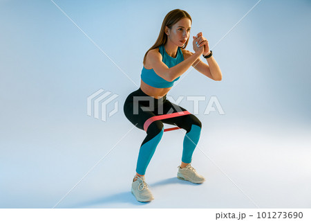 Athletic woman trains legs with fitness elastic band on studio background Athletic woman trains legs with fitness elastic band on studio background 101273690