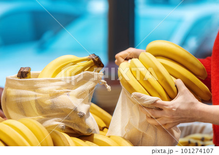 Woman picking bananas in a reusable bag. Ecology, Earth Day thematics Woman picking bananas in a reusable bag. Ecology, Earth Day thematics 101274107